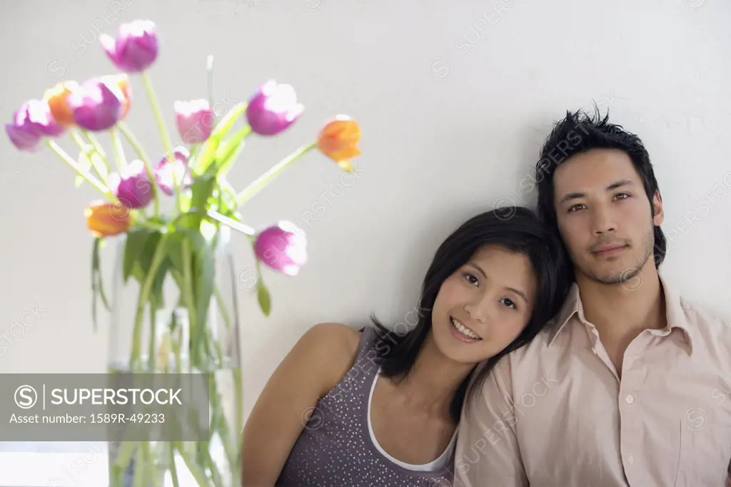 Asian couple next to flowers in vase
