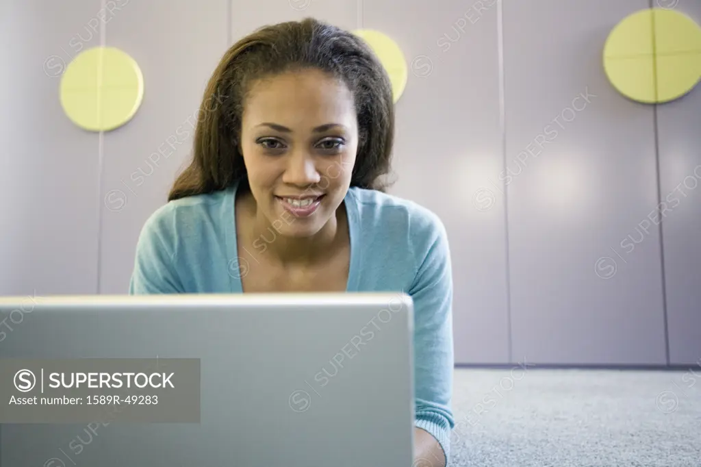 African American woman using laptop on floor