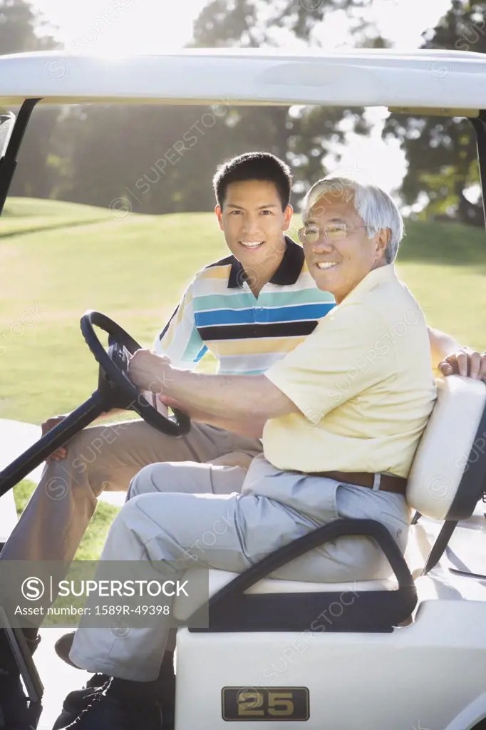 Asian father and adult son in golf cart