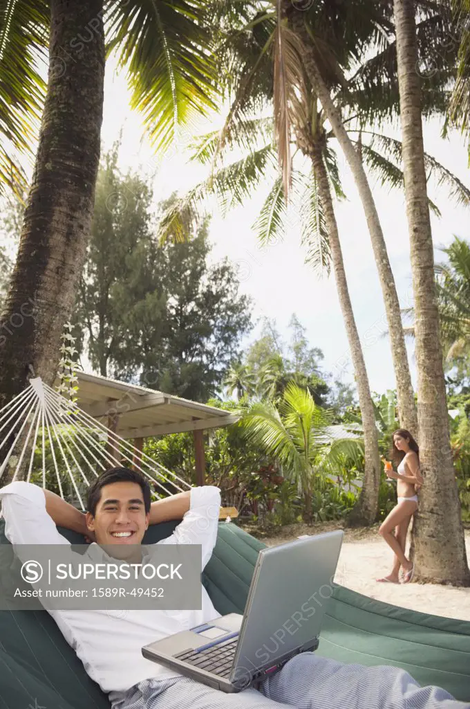 Asian man with laptop in hammock