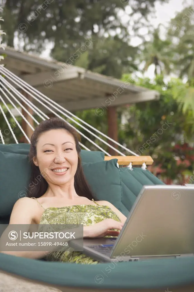 Asian woman with laptop in hammock