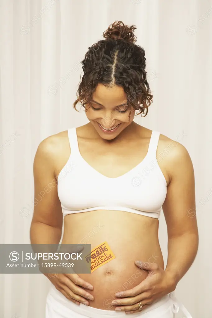 Pregnant Mixed Race woman with fragile sticker on belly