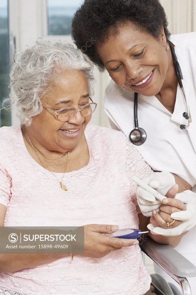 Doctor testing African American womans blood sugar