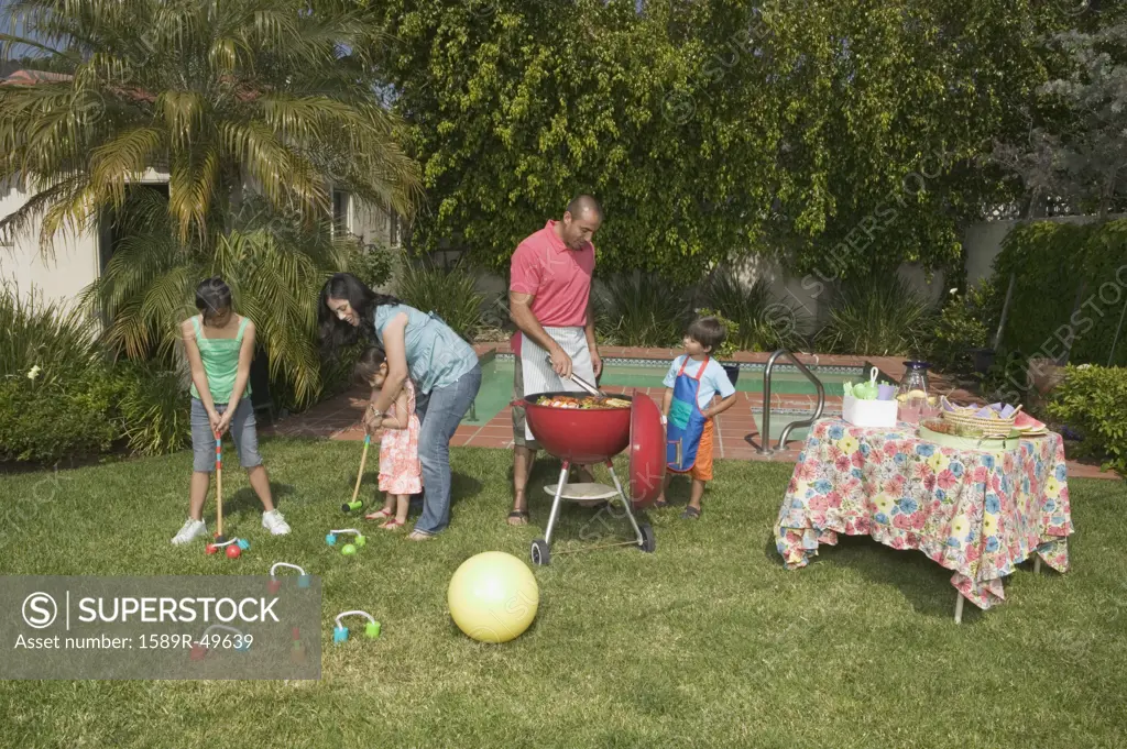 Hispanic family barbequing and playing croquet