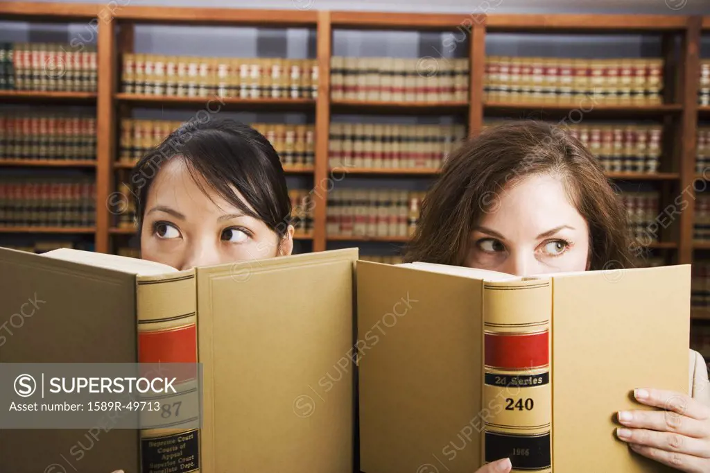 Multi-ethnic women holding library reference book