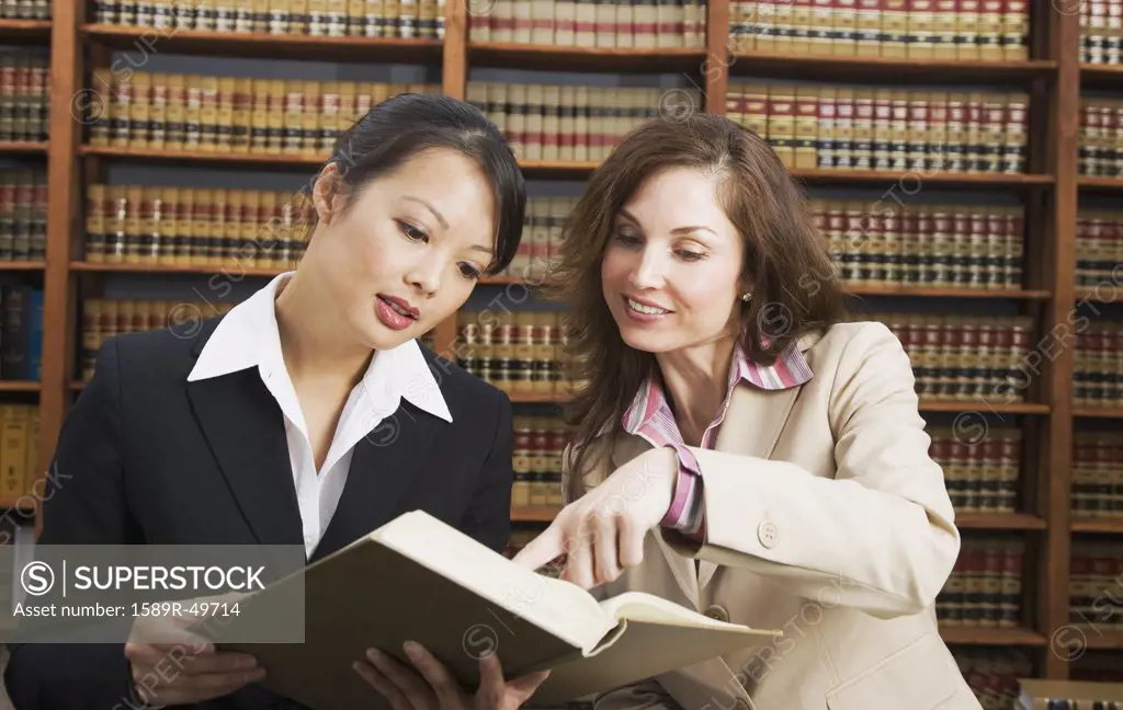 Multi-ethnic women looking at library reference book