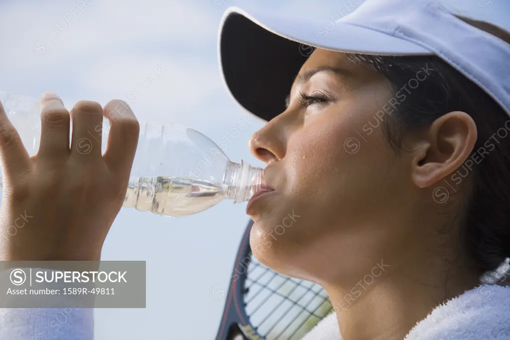 Hispanic woman drinking from water bottle