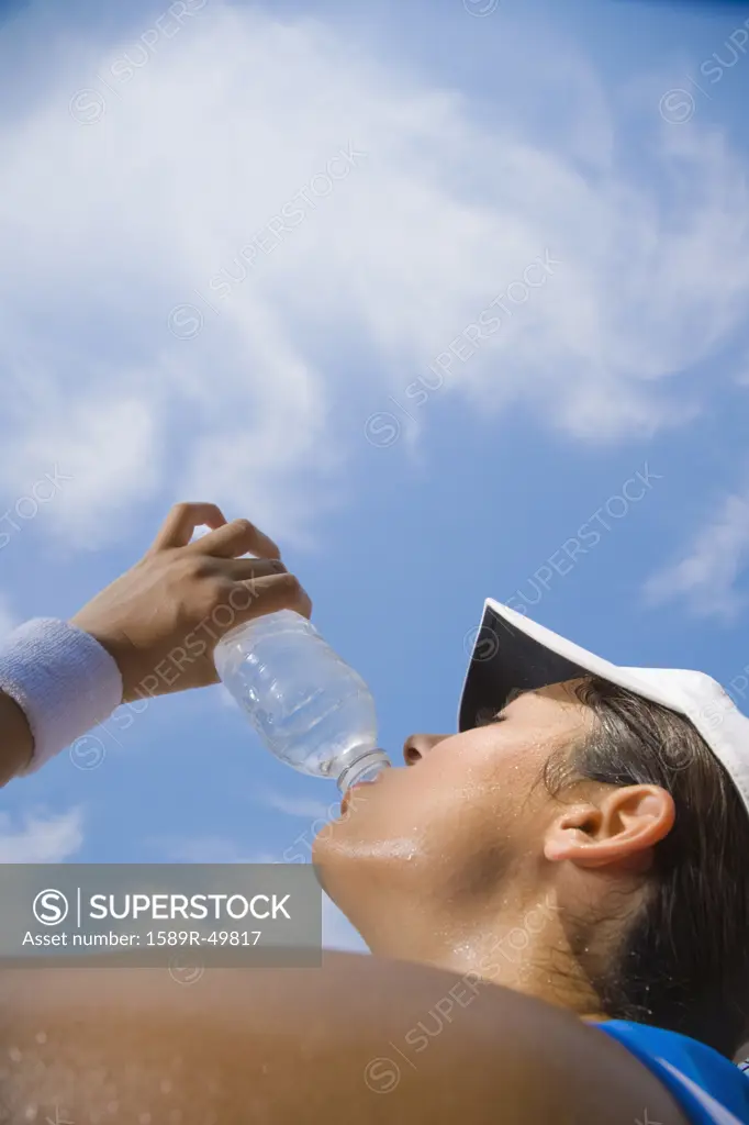 Hispanic woman drinking from water bottle