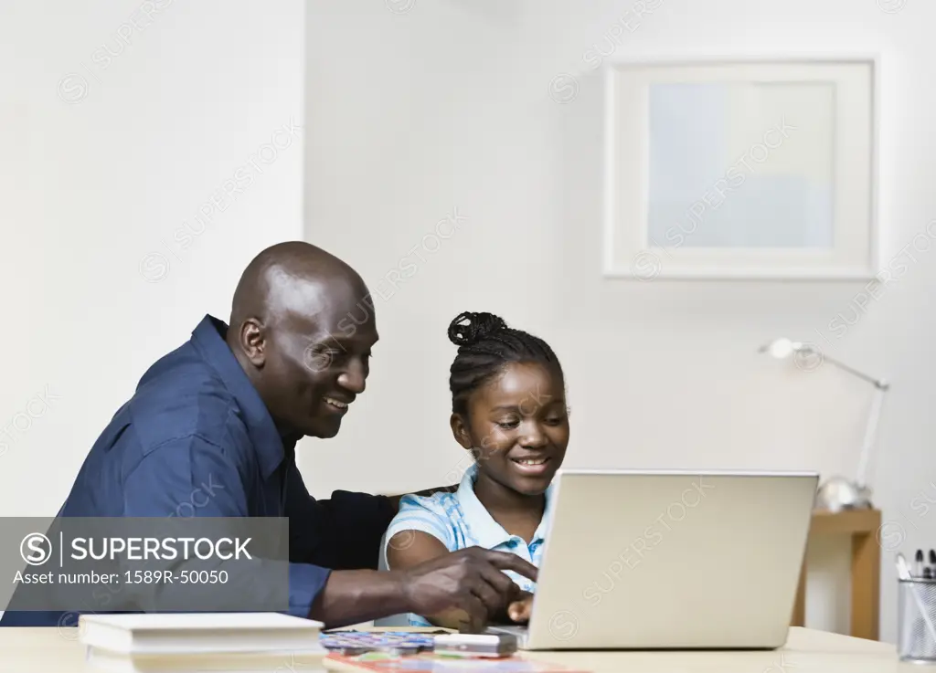 African father and daughter looking at laptop