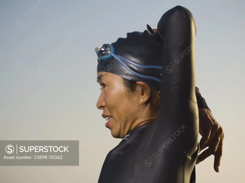 Asian woman stretching in wetsuit and goggles