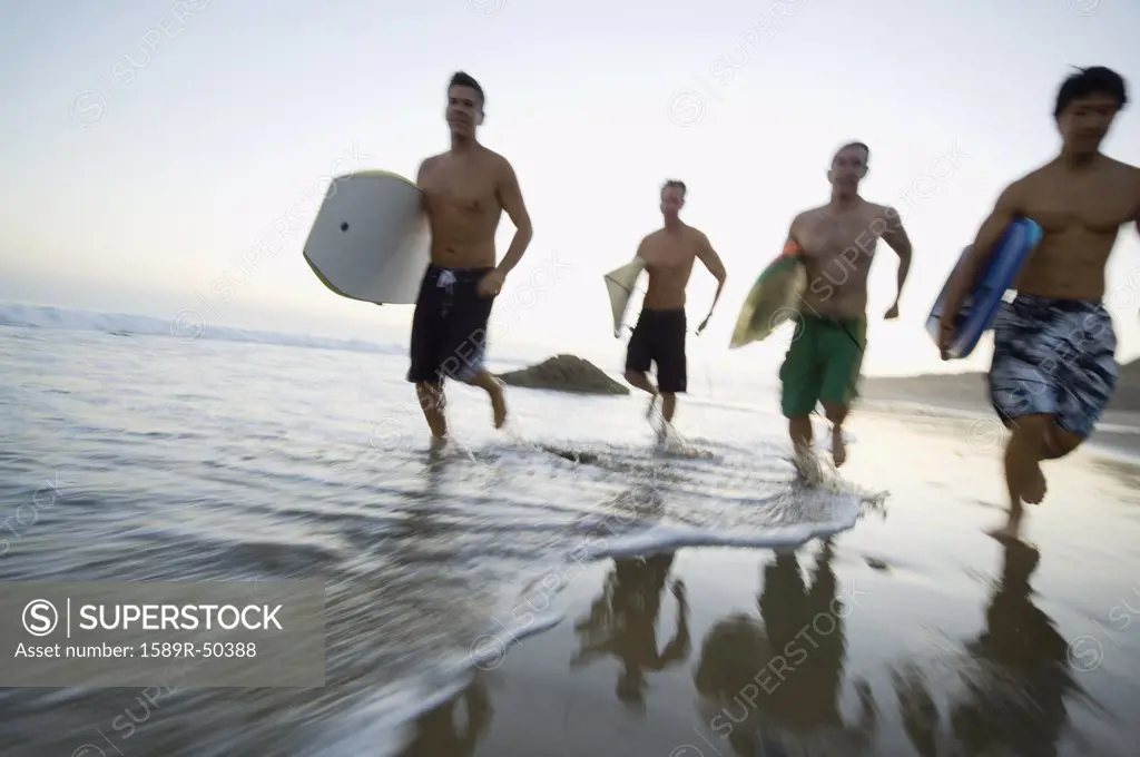 Multi-ethnic men running with surfboards