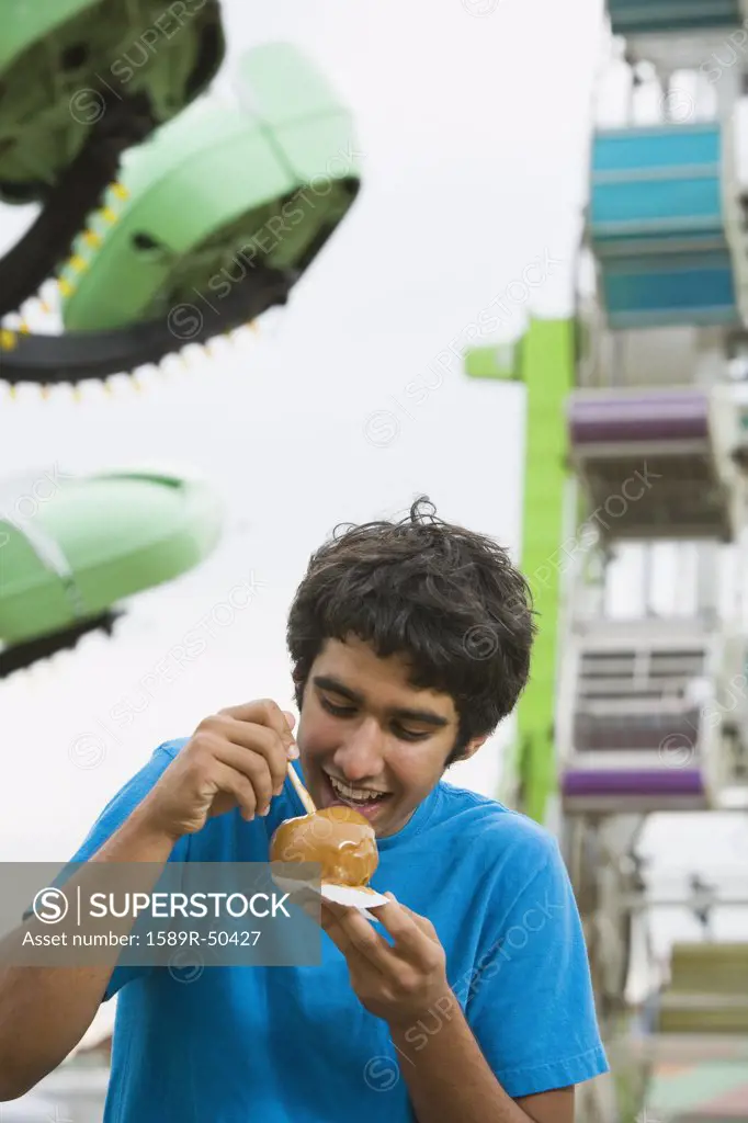 Mixed Race teenaged boy eating candied apple