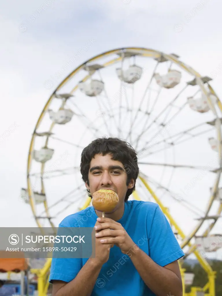 Mixed Race teenaged boy eating candied apple