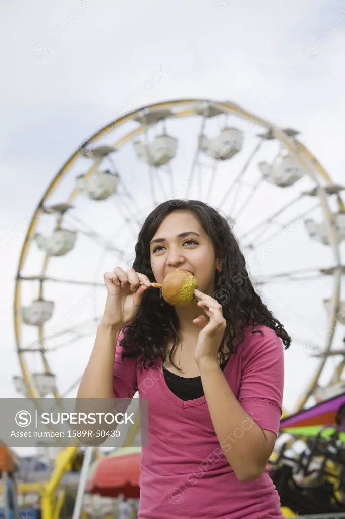Mixed Race teenaged girl eating candied apple