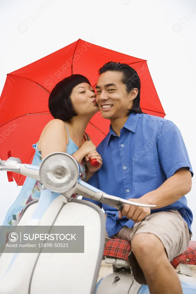Asian woman kissing boyfriend on cheek
