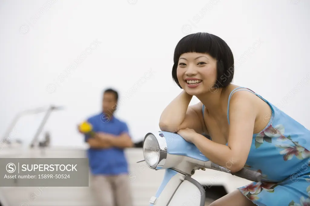 Asian woman sitting on motor scooter