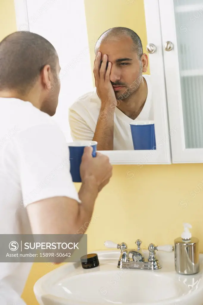 Middle Eastern man looking in mirror