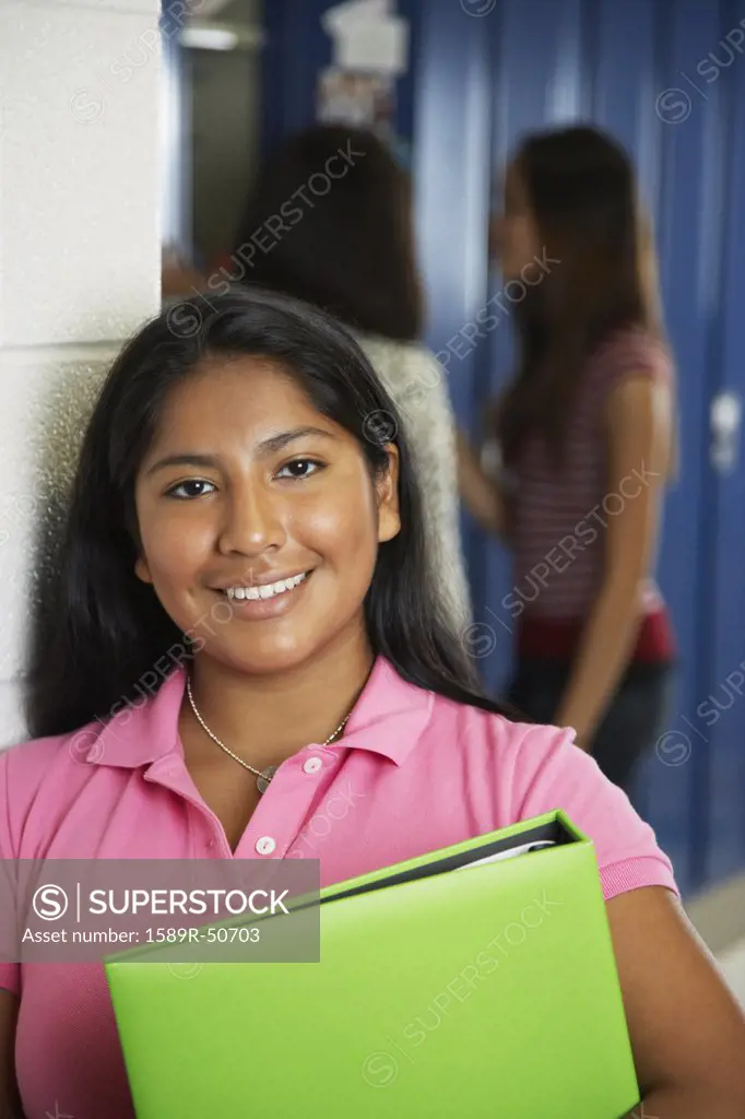 Hispanic teenaged girl holding school books