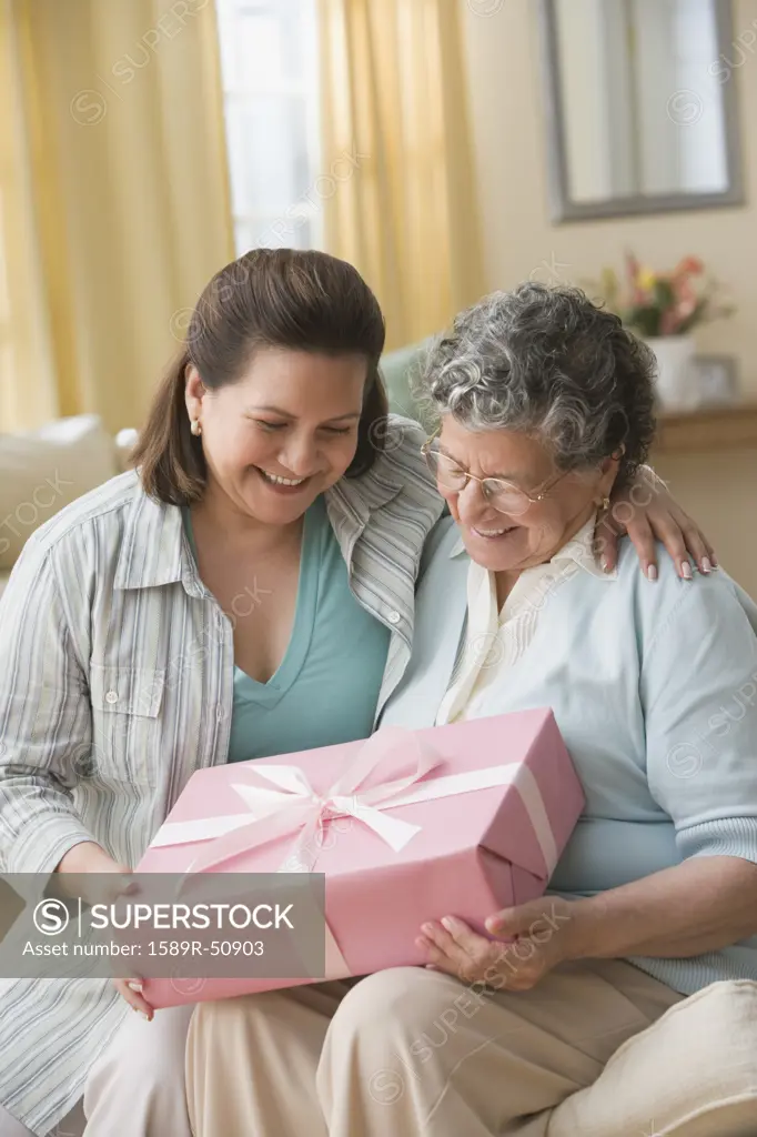 Hispanic mother and adult daughter exchanging gift