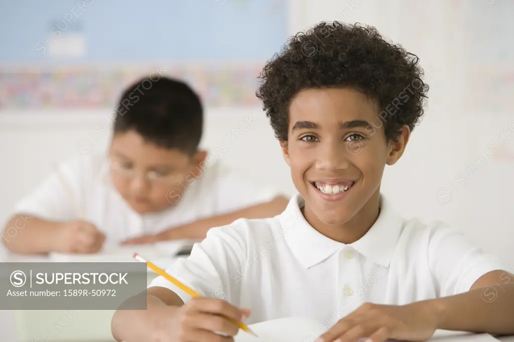 Hispanic boy writing at school desk