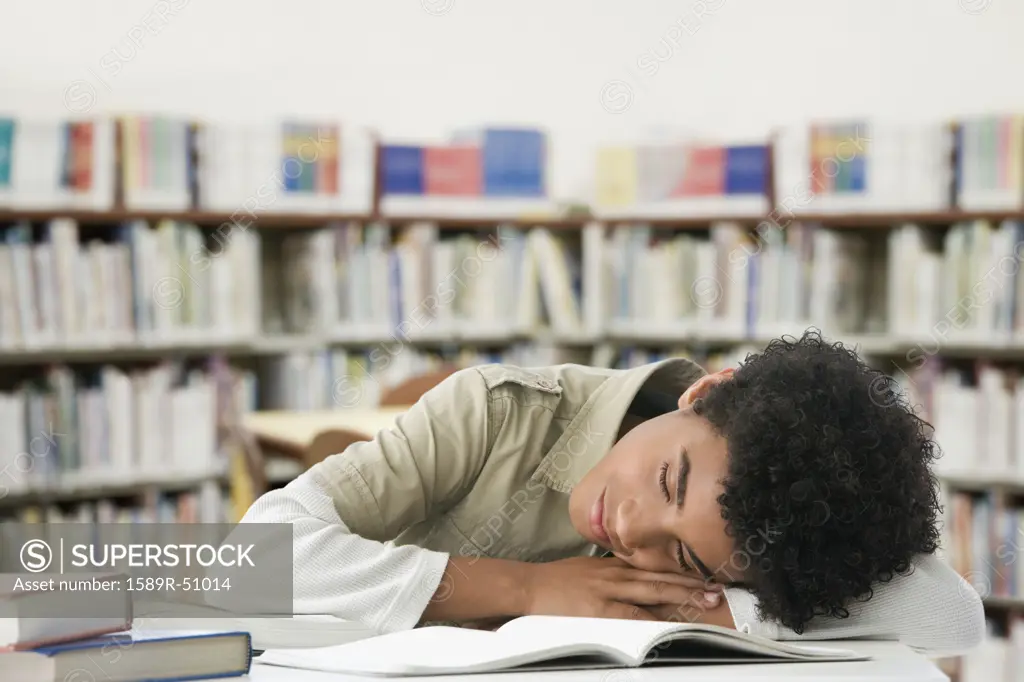Hispanic boy sleeping in library