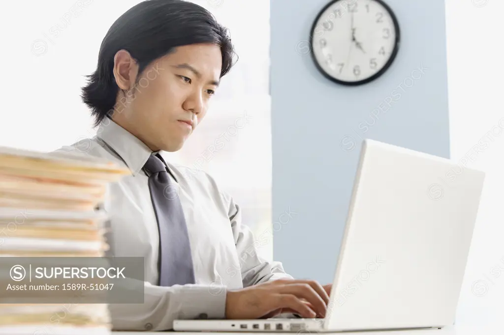 Asian businessman typing on laptop