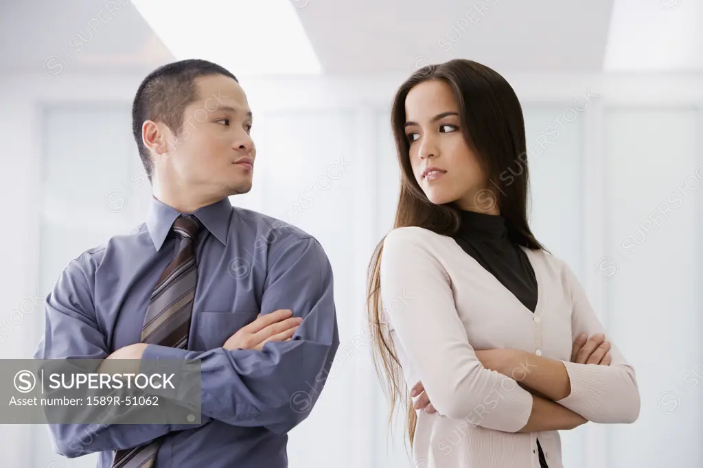 Multi-ethnic businesspeople looking over shoulders at each other