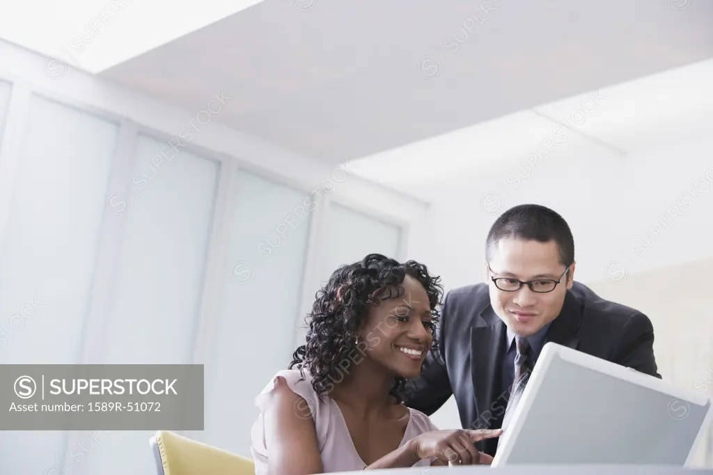 Multi-ethnic businesspeople looking at laptop