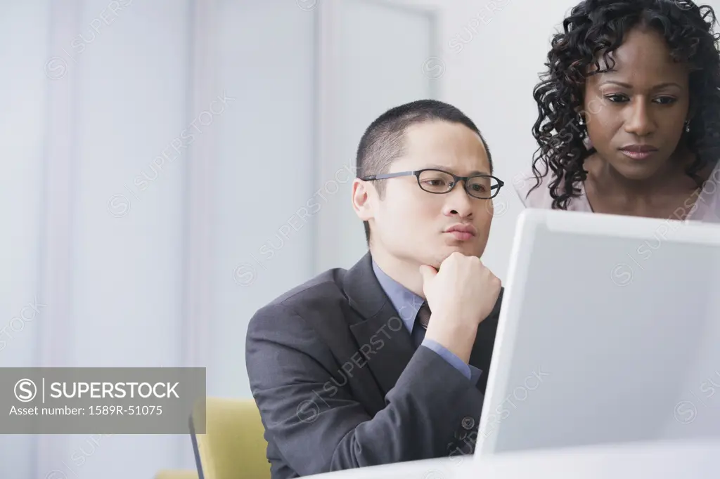 Multi-ethnic businesspeople looking at laptop