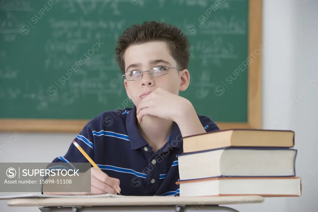 Hispanic boy writing at school desk