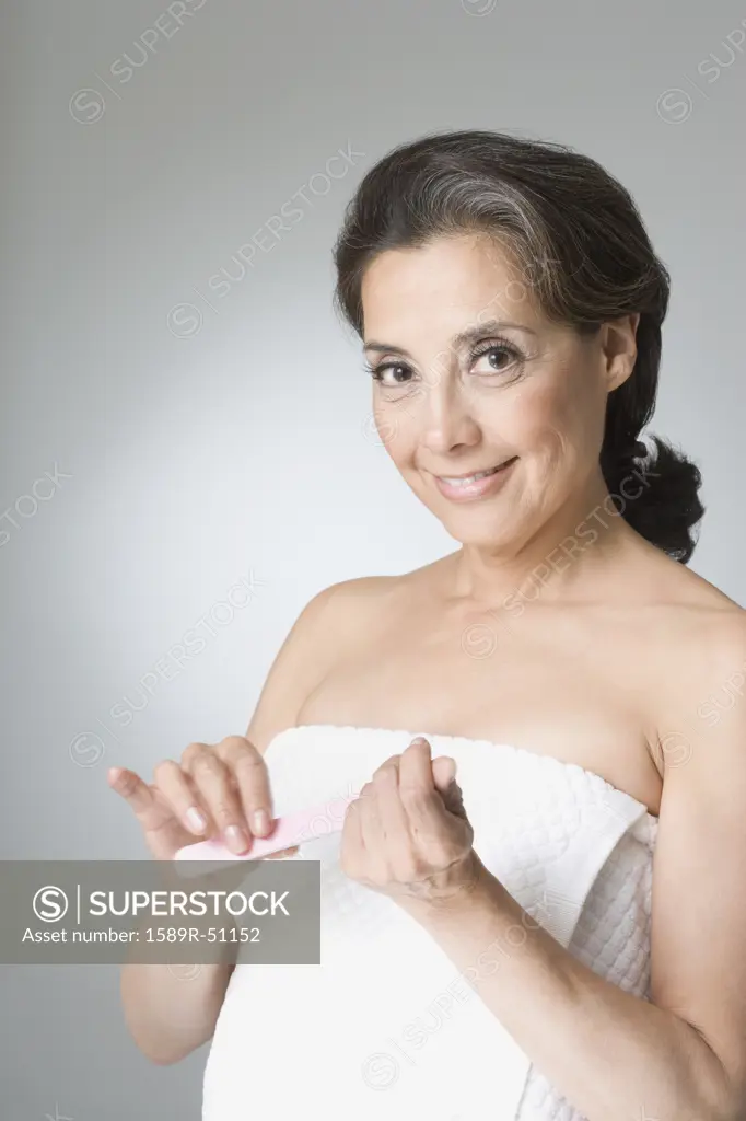Hispanic woman filing fingernails