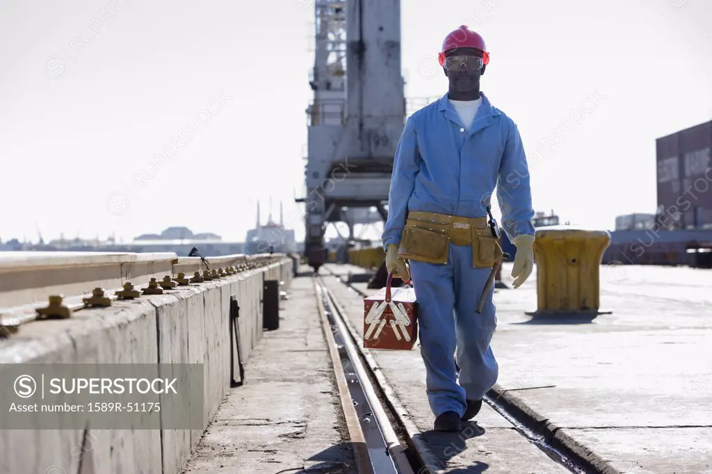 African American male construction worker carrying toolbox