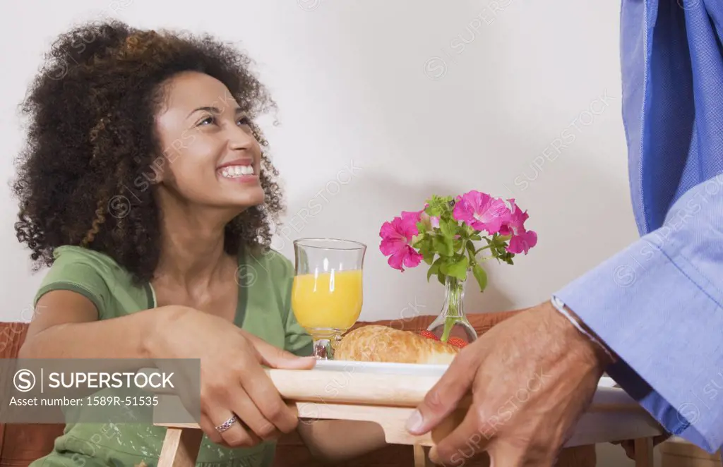 African man bringing breakfast in bed to wife