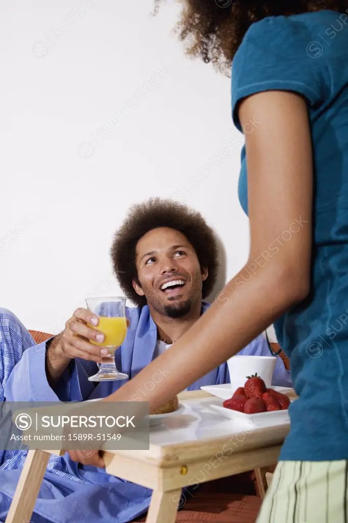African woman bringing breakfast in bed to husband