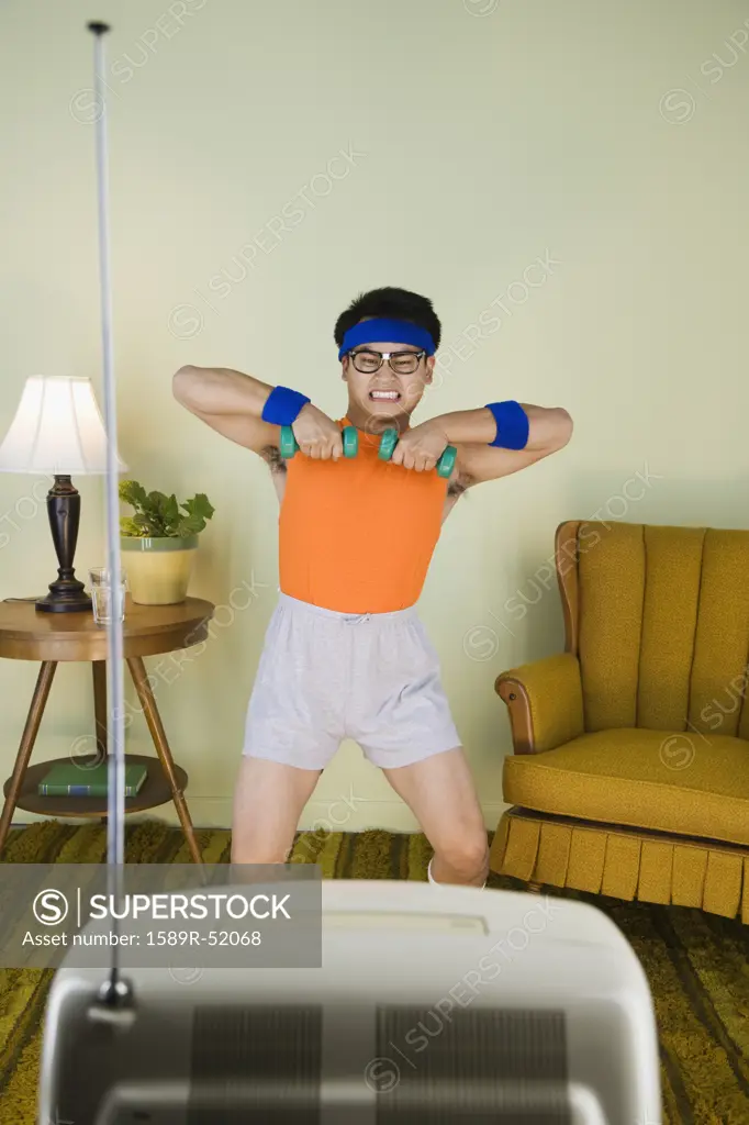 Nerdy Asian man exercising in front of television