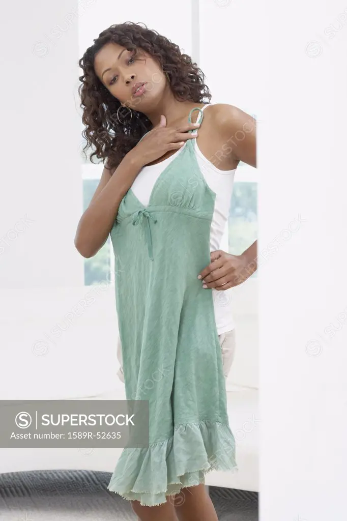 African woman looking at dress in mirror