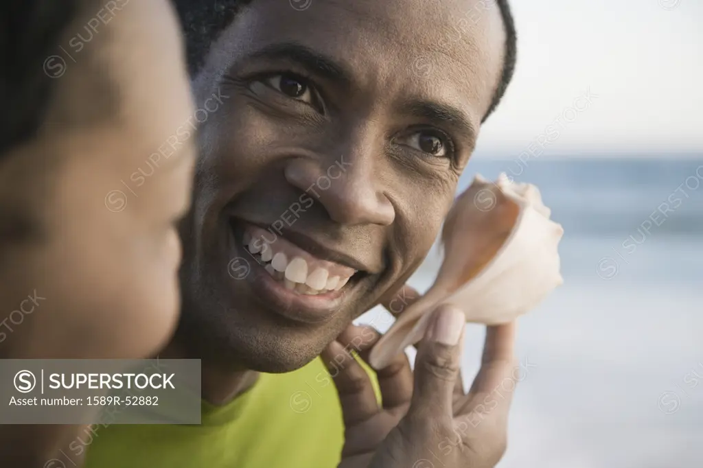 African man listening to seashell