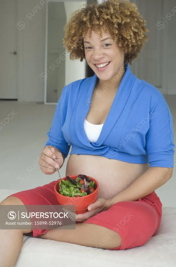 Pregnant African woman eating salad