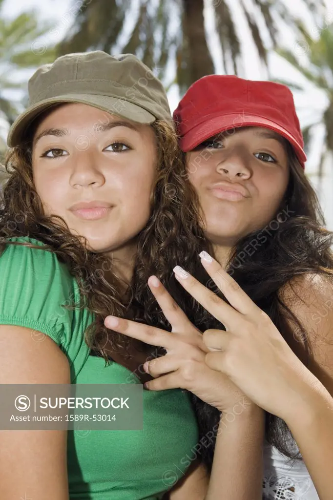 Hispanic teenaged girls making hand gestures