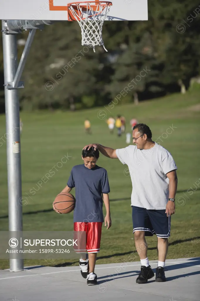 Hispanic father and son on basketball court