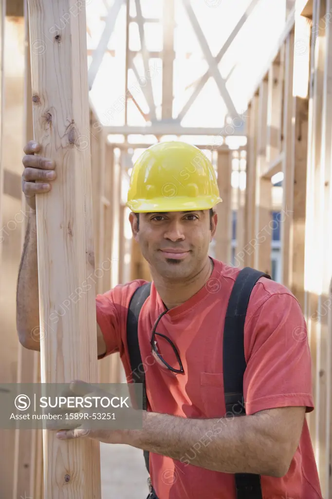 Mixed Race male construction worker holding lumber