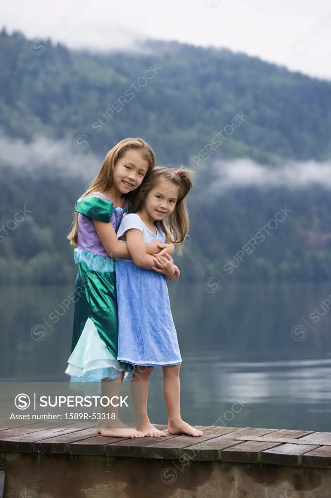 Asian sisters hugging on dock