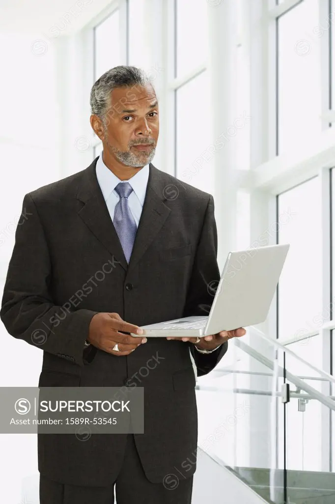 African businessman holding laptop