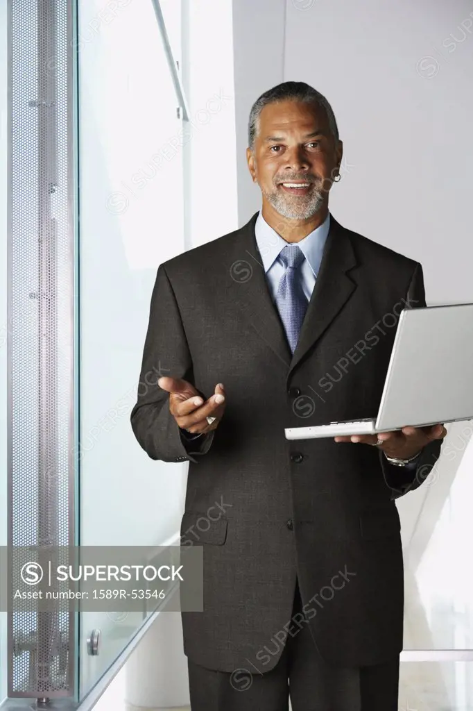 African businessman holding laptop