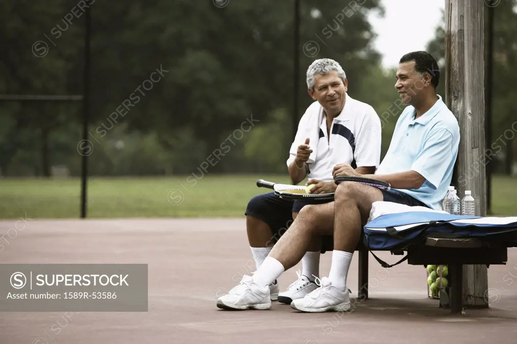 Multi-ethnic men talking on tennis court
