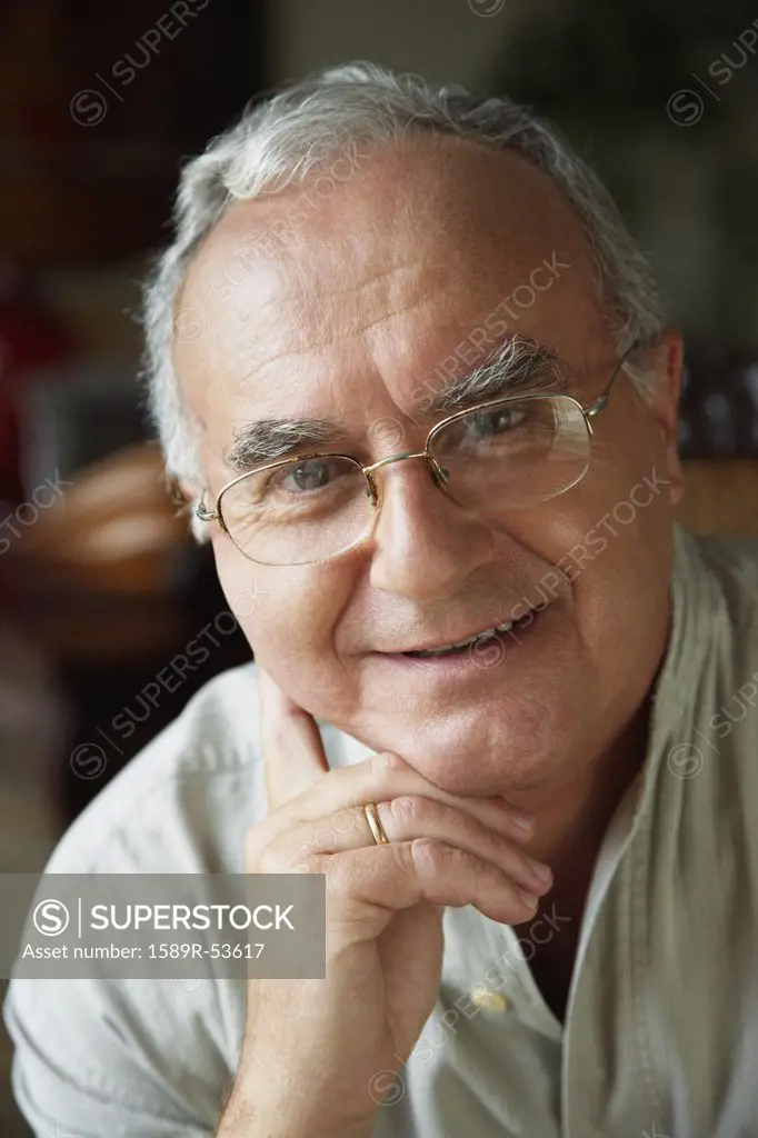 Senior Hispanic man leaning chin on hand