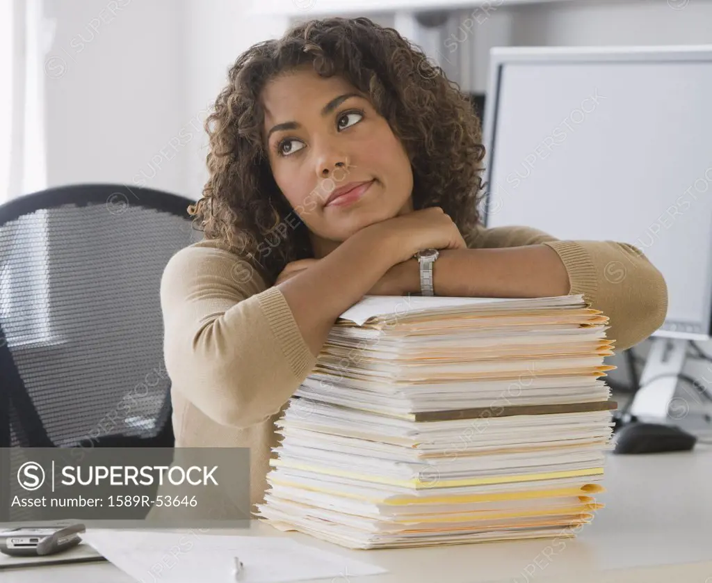 African businesswoman leaning on stack of paperwork