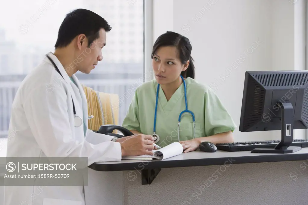 Asian doctors talking at desk