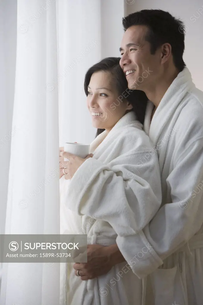 Asian couple in bathrobes hugging