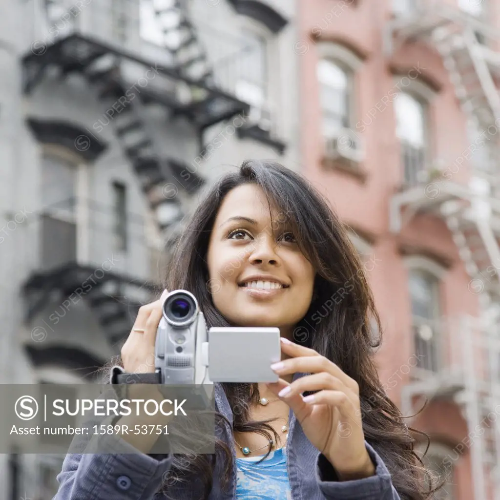 Mixed Race woman holding video camera